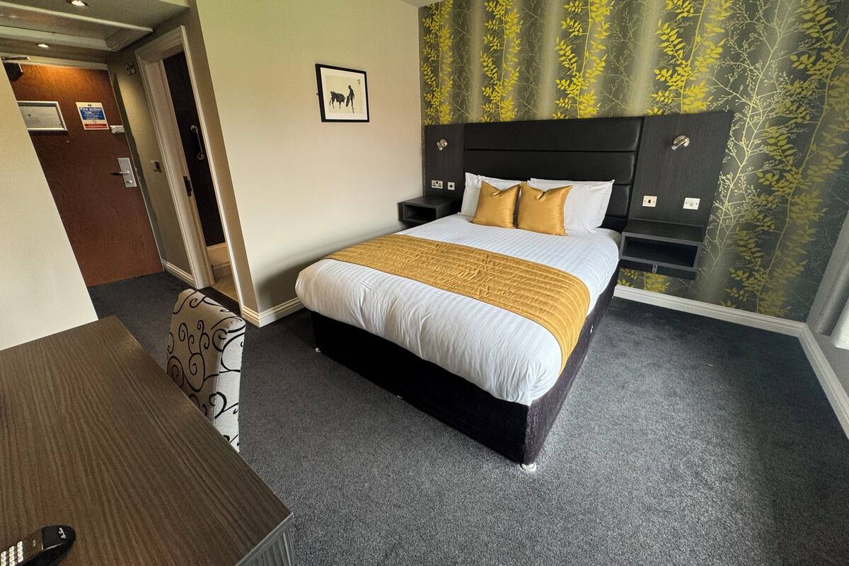 A hotel room with a bed, a desk, and a door leading to a bathroom.