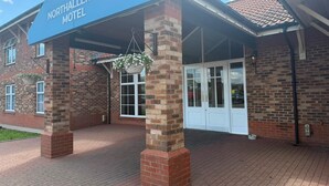 A brick building with a blue sign reading 'Northallerton Motel' and a covered entrance. - Northallerton Motel (Northallerton)