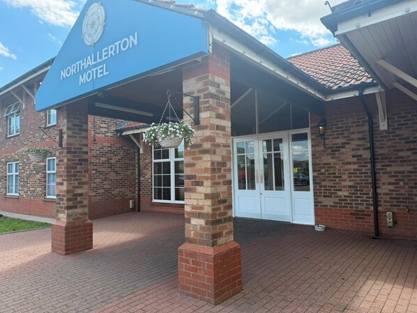 A brick building with a blue sign reading 'Northallerton Motel' and a covered entrance.