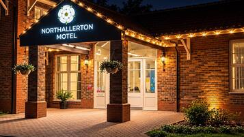The exterior of Northallerton Hotel with a brick facade, a marquee sign, and outdoor lighting.