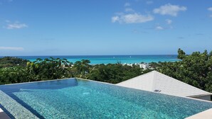 An infinity pool with a clear view of the ocean and distant sailboats. - Villa Fair Winds (Jolly Harbour)