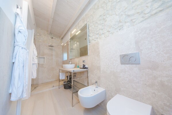 Un baño moderno con ducha de vidrio, lavamanos blanco y bidé.