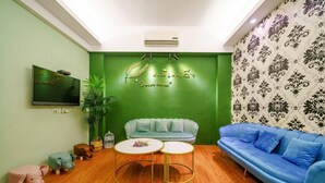 A cozy living room with a green accent wall, a blue sofa, a light green couch, and a small round table. - Silver Netherlands B and B (Luodong)