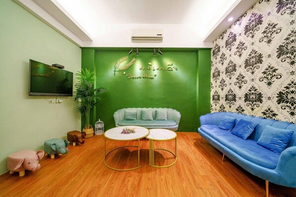A cozy living room with a green accent wall, a blue sofa, a light green couch, and a small round table. - Silver Netherlands B and B (Luodong)