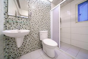 A bathroom with a tiled mosaic wall, a white sink, and a toilet. - Silver Netherlands B and B (Luodong)