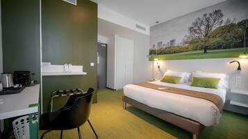 Une chambre d’hôtel avec un lit, un bureau, une chaise et un tableau représentant un parc.