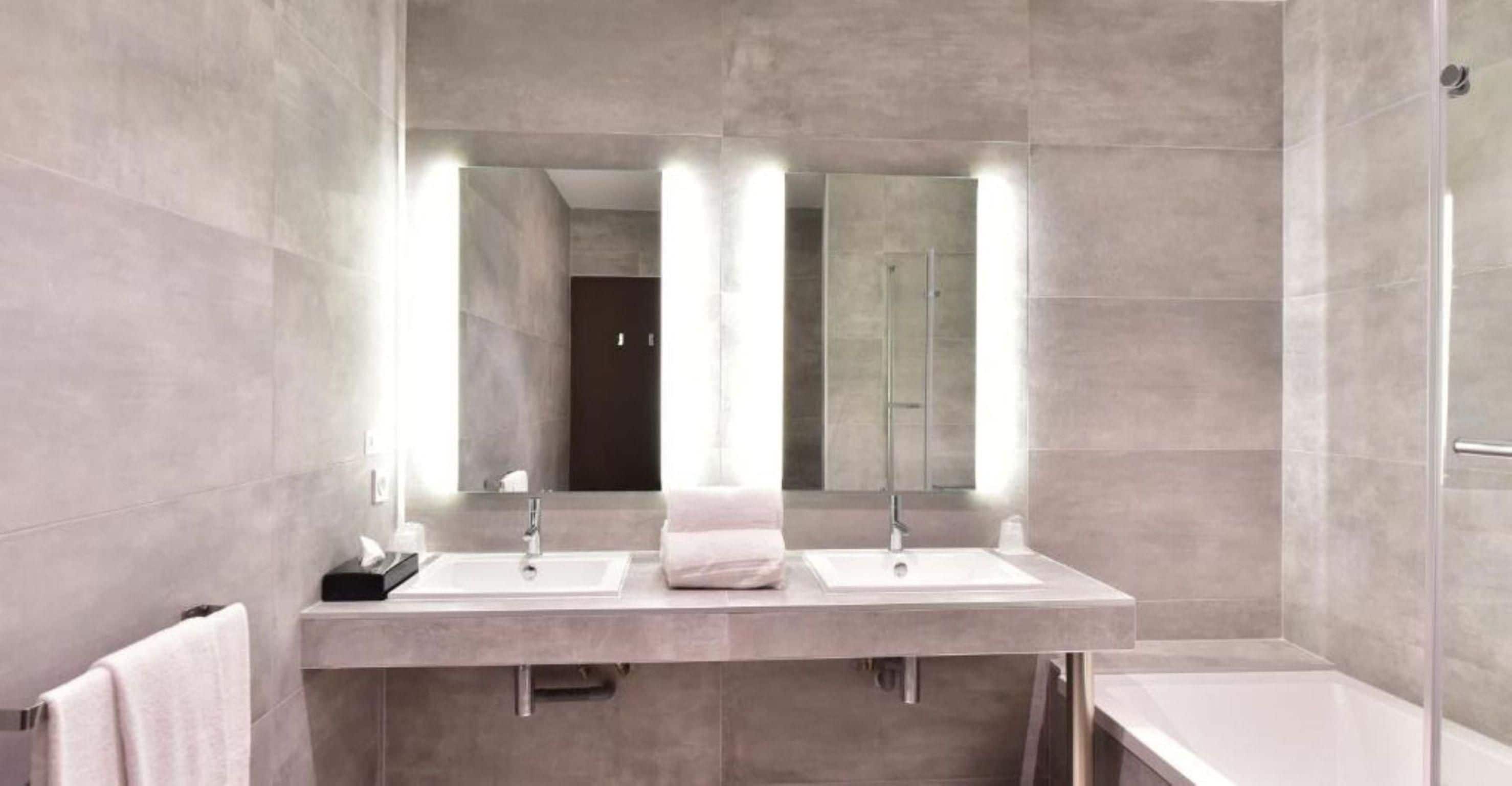 Casa de banho moderna com duas pias, um espelho e um chuveiro.