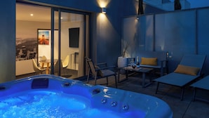 A hot tub with a cityscape view, outdoor seating, and a glass door leading to an interior space. - Best Western Plus Central Park Hotel & Spa (La Rochelle)