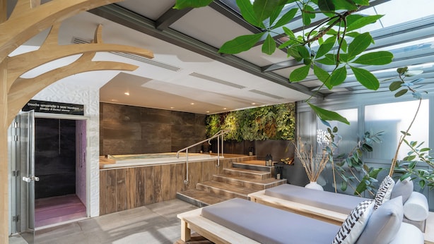 A spa area with a wooden bench, a shower, and a staircase leading to a balcony. - Best Western Plus Central Park Hotel & Spa (La Rochelle)