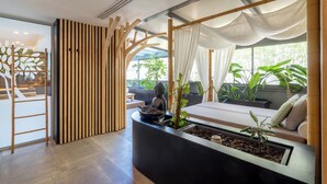 A modern interior with a reception desk, a wooden slat partition, a seating area with cushions, and a large window with plants. - Best Western Plus Central Park Hotel & Spa (La Rochelle)
