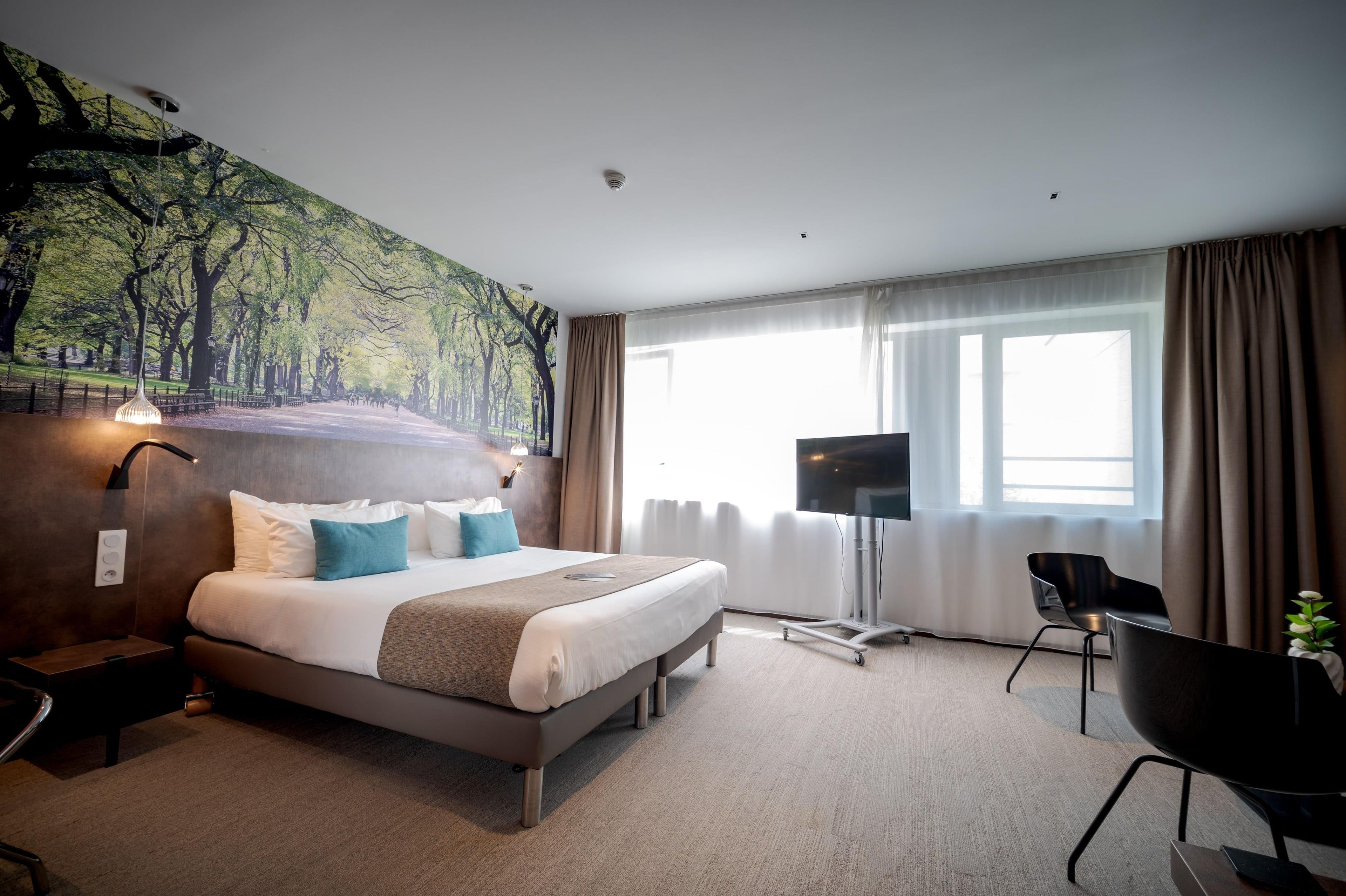 A hotel room with a large bed, a flat-screen TV, a desk, and a chair.