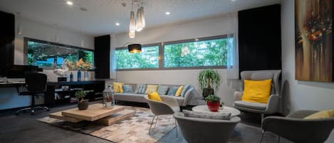 A modern living room with a sofa, chairs, a coffee table, and a TV.
