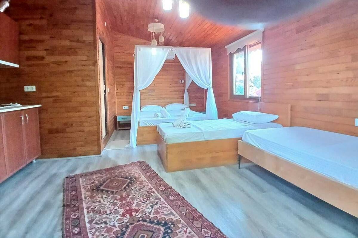 A wooden cabin bedroom with a bed, a bedside table, and a window.