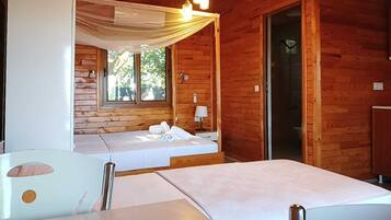 Quarto de cabana de madeira com duas camas, uma mesa e uma janela.