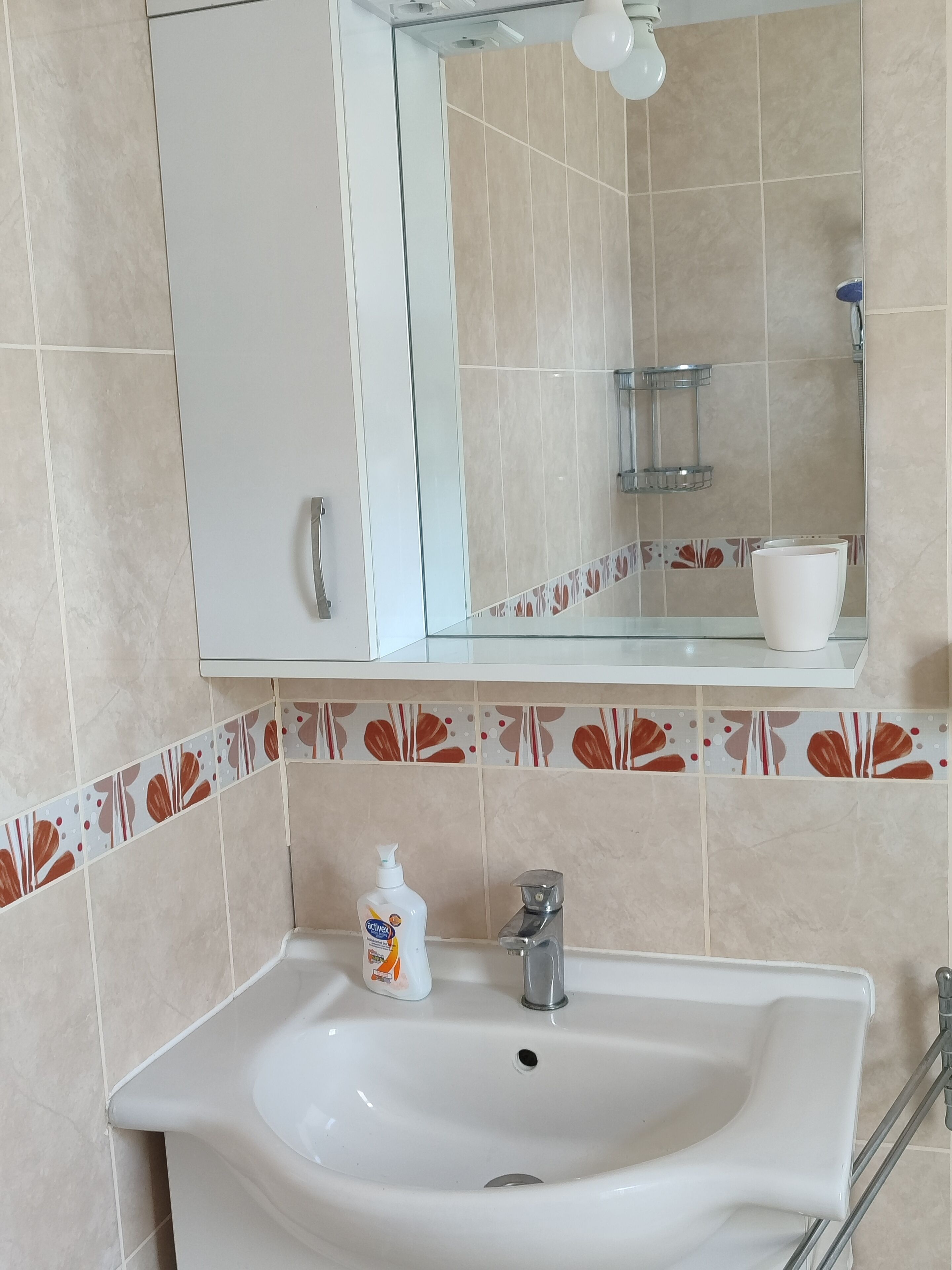 Un baño con lavamanos blanco, un espejo y un secador de manos.