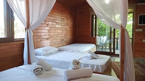 Una cabaña de madera con dos camas, cada una con ropa blanca y toallas, y un balcón con una mesa y sillas.