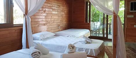 Una cabaña de madera con dos camas, cada una con ropa blanca y toallas, y un balcón con una mesa y sillas.