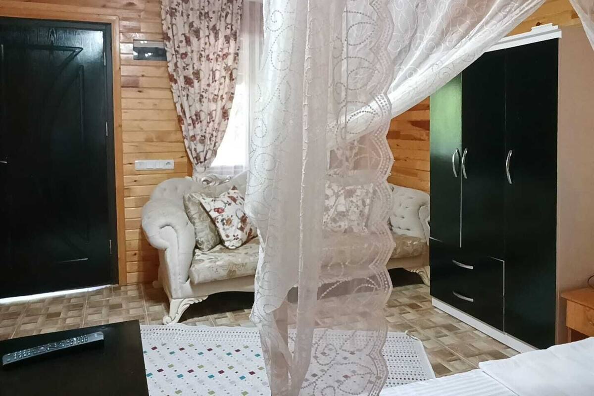 A bedroom with a bed, a wardrobe, a sofa, and a window with curtains.