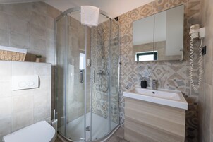 Ein modernes Badezimmer mit einer Duschkabine aus Glas, einem weißen Waschbecken und einer gefliesten Rückwand mit Muster.