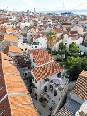 A high-rise building with a rooftop terrace, multiple balconies, and a view of the cityscape.