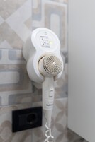 Ein weißer Haartrockner an einer Wand, die mit einem gemusterten Fliesenbild verziert ist.