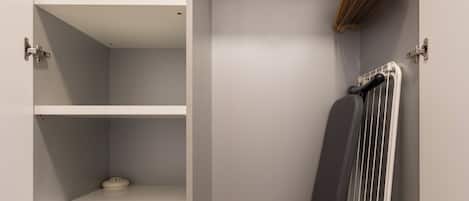 A closet with shelves, a hanging rack, and a radiator.