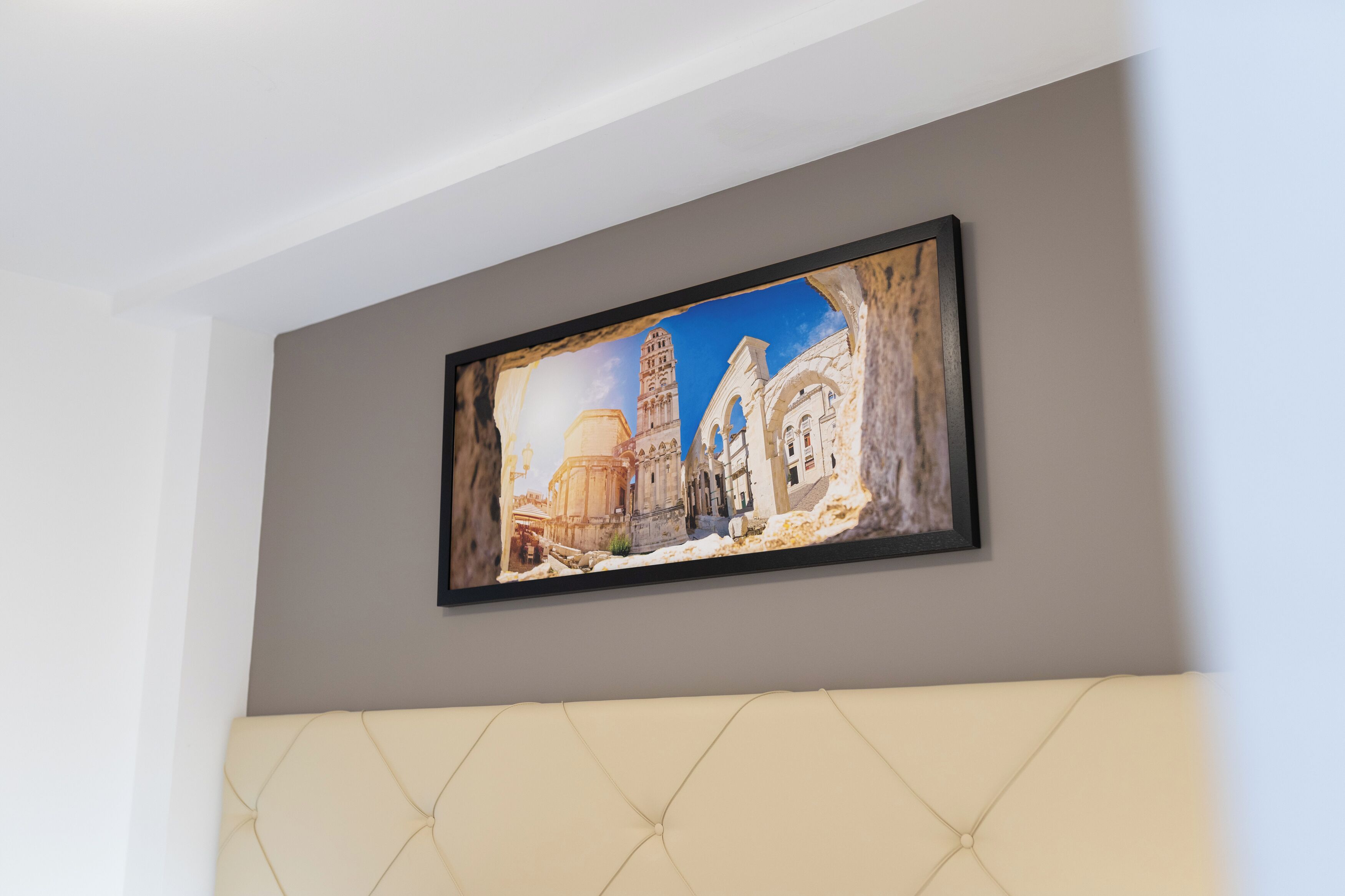 A framed painting of a historical building on a wall.