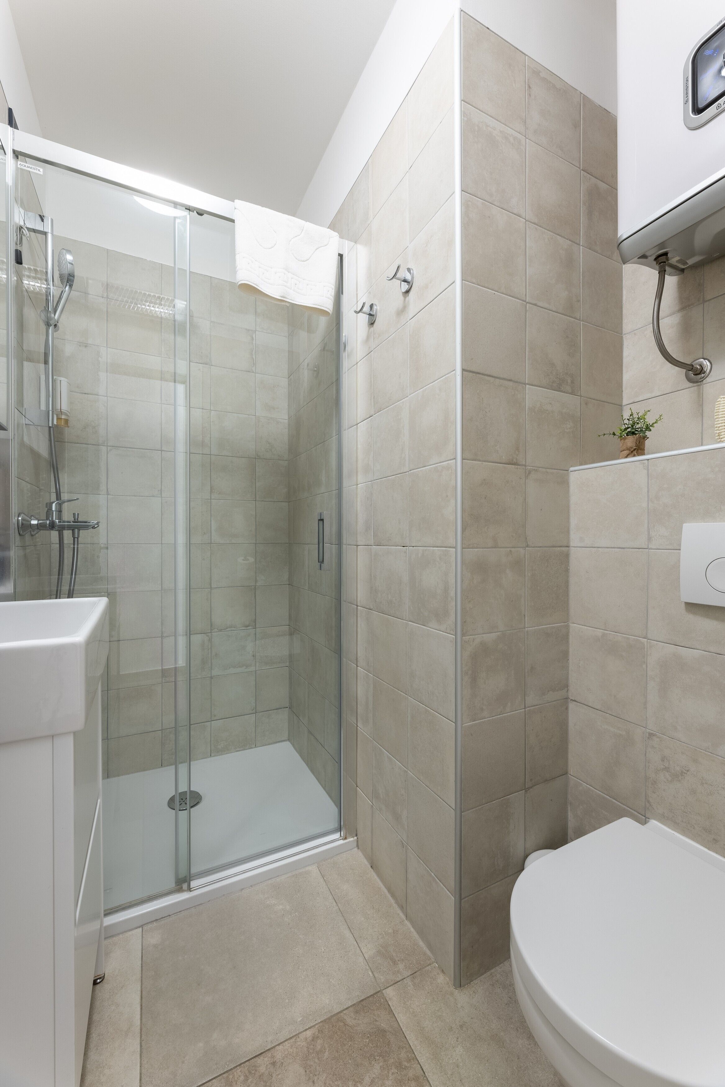 A modern bathroom with a glass-enclosed shower, a white toilet, and a sink.