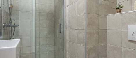 A modern bathroom with a glass-enclosed shower, a white toilet, and a sink.