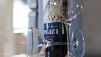 Una bottiglia di vino NIKO LICA e due bicchieri da vino su un tavolo.