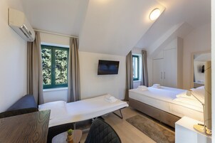 Hotellihuone, jossa on kaksi sänkyä, työpöytä, televisio ja peili.