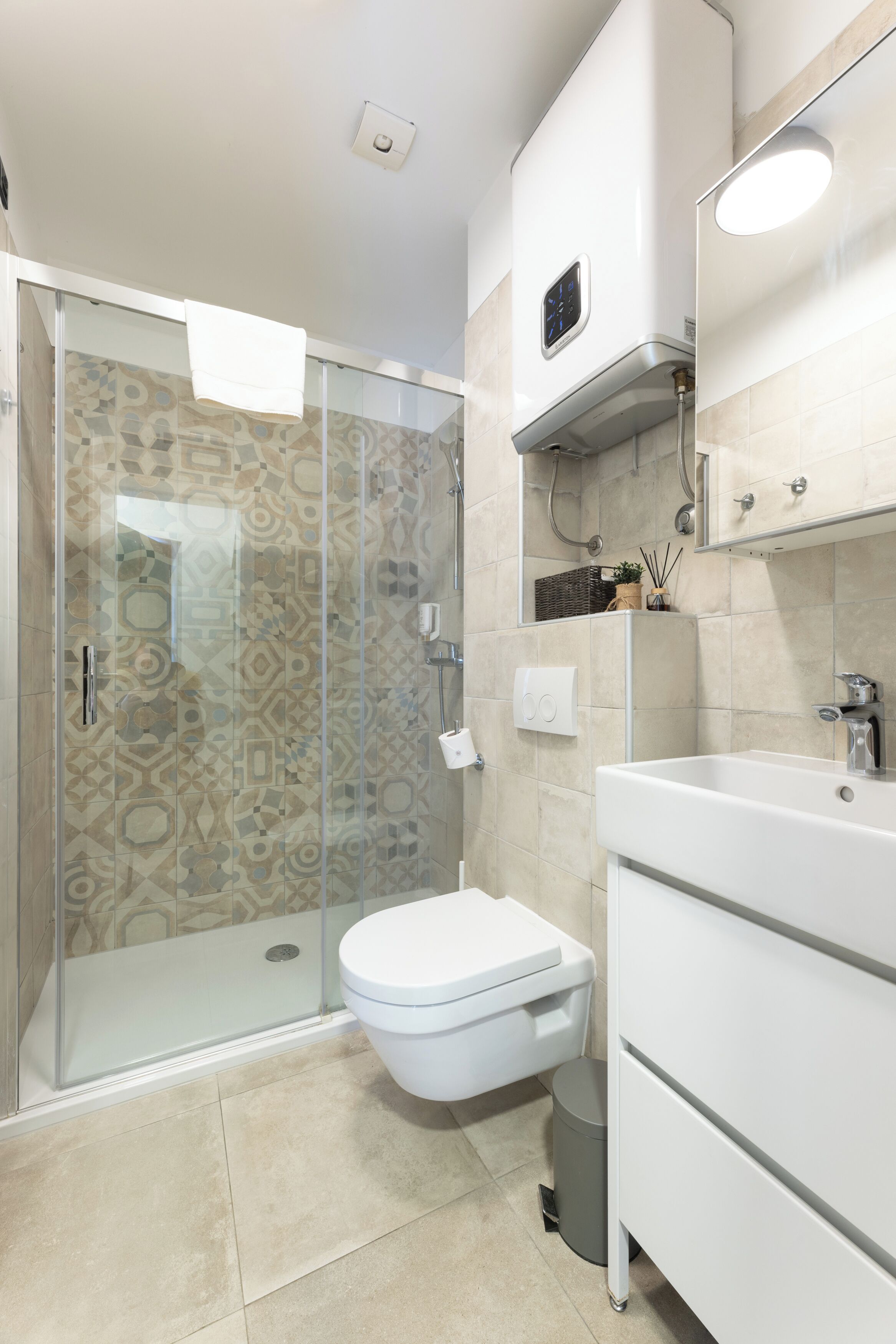 A modern bathroom with a glass-enclosed shower, a white toilet, and a vanity with a mirror.