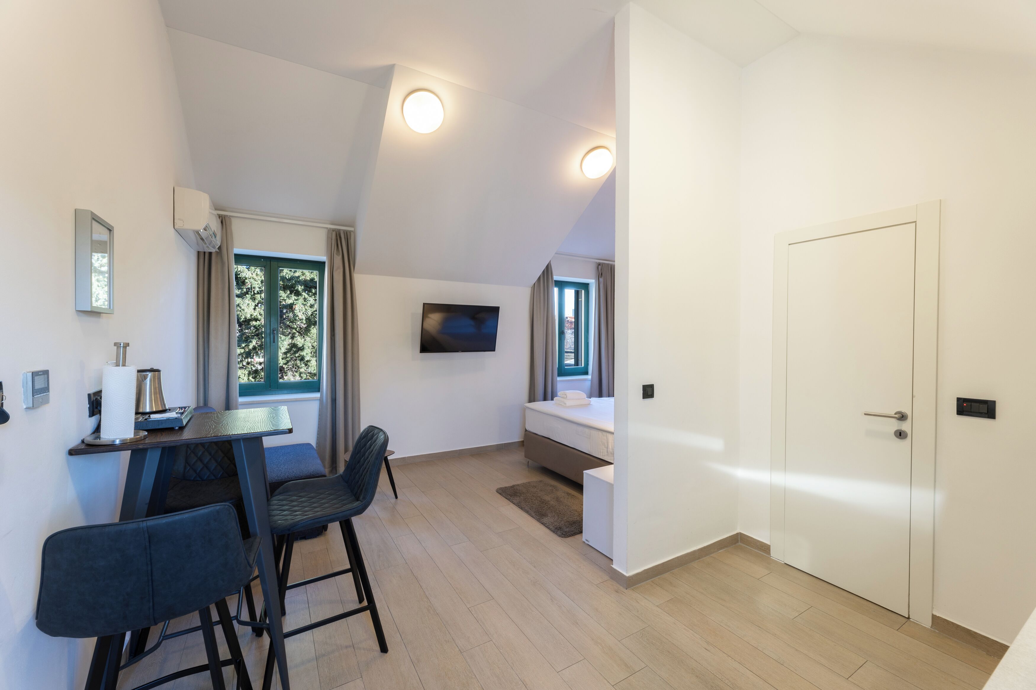 Una habitación moderna con comedor, cama y televisor fijado a la pared.