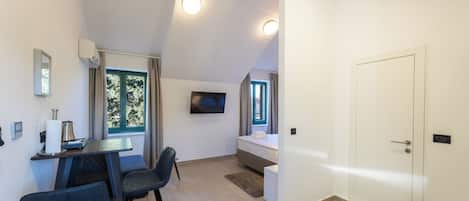 Een moderne kamer met een eethoek, een bed en een aan de muur bevestigde televisie.