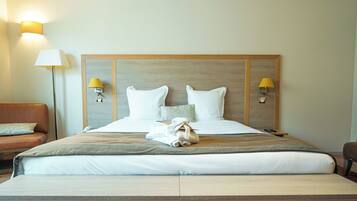 A hotel room with a large bed, two bedside lamps, a wooden headboard, a brown leather sofa, and a small table.