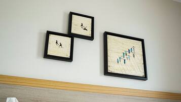 Een hotelkamer met een bed, twee kussens en drie kunstwerken in lijsten aan de muur.