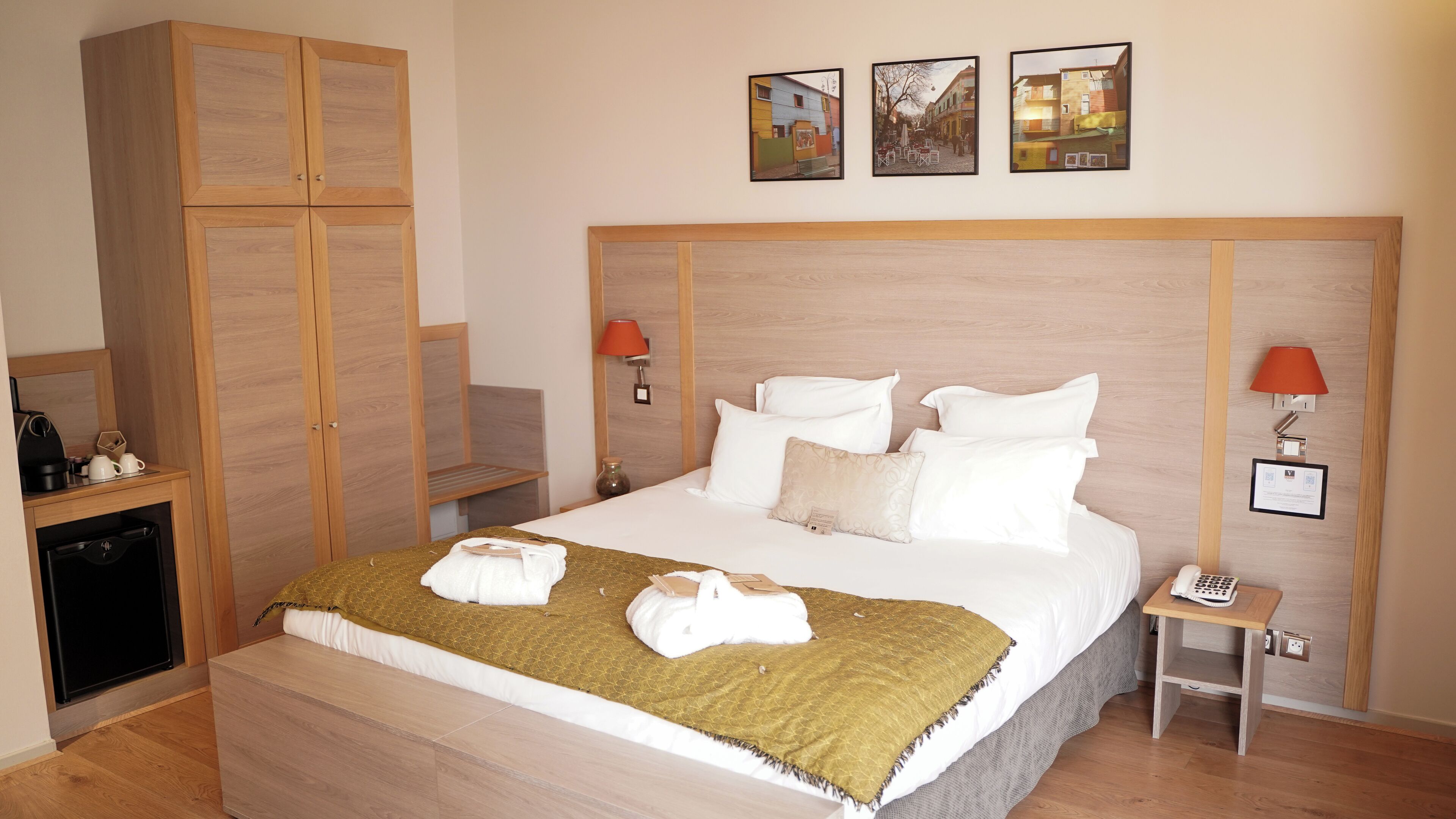 Una camera d'albergo con un letto grande, due comodini, un armadio e una televisione a parete.