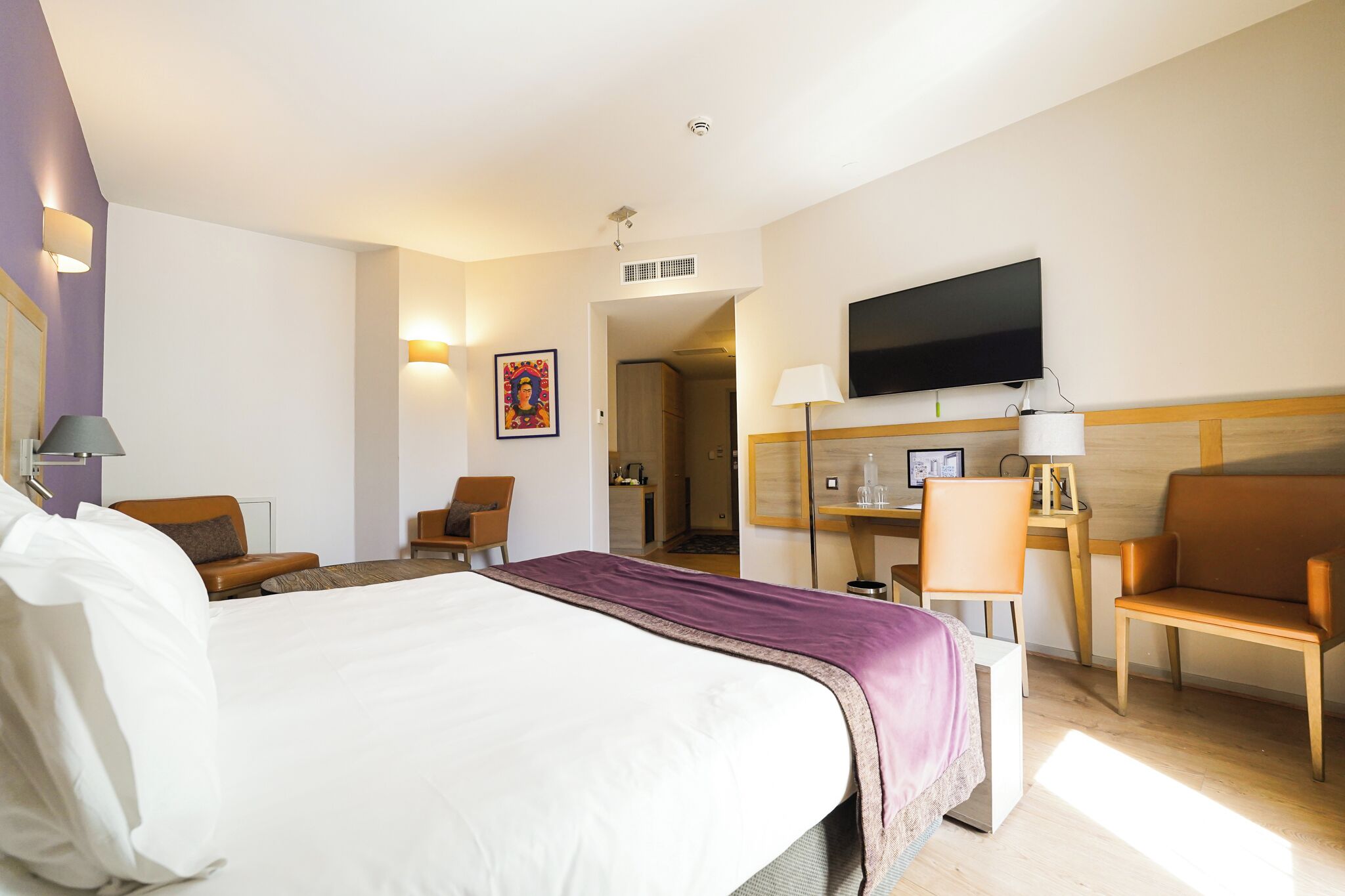 Una habitación de hotel con una cama grande, un escritorio con computadora, un televisor y una silla.