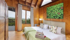 A wooden room with a bed, a balcony, and a painting of greenery. - ArendsRus Country Lodge (George)