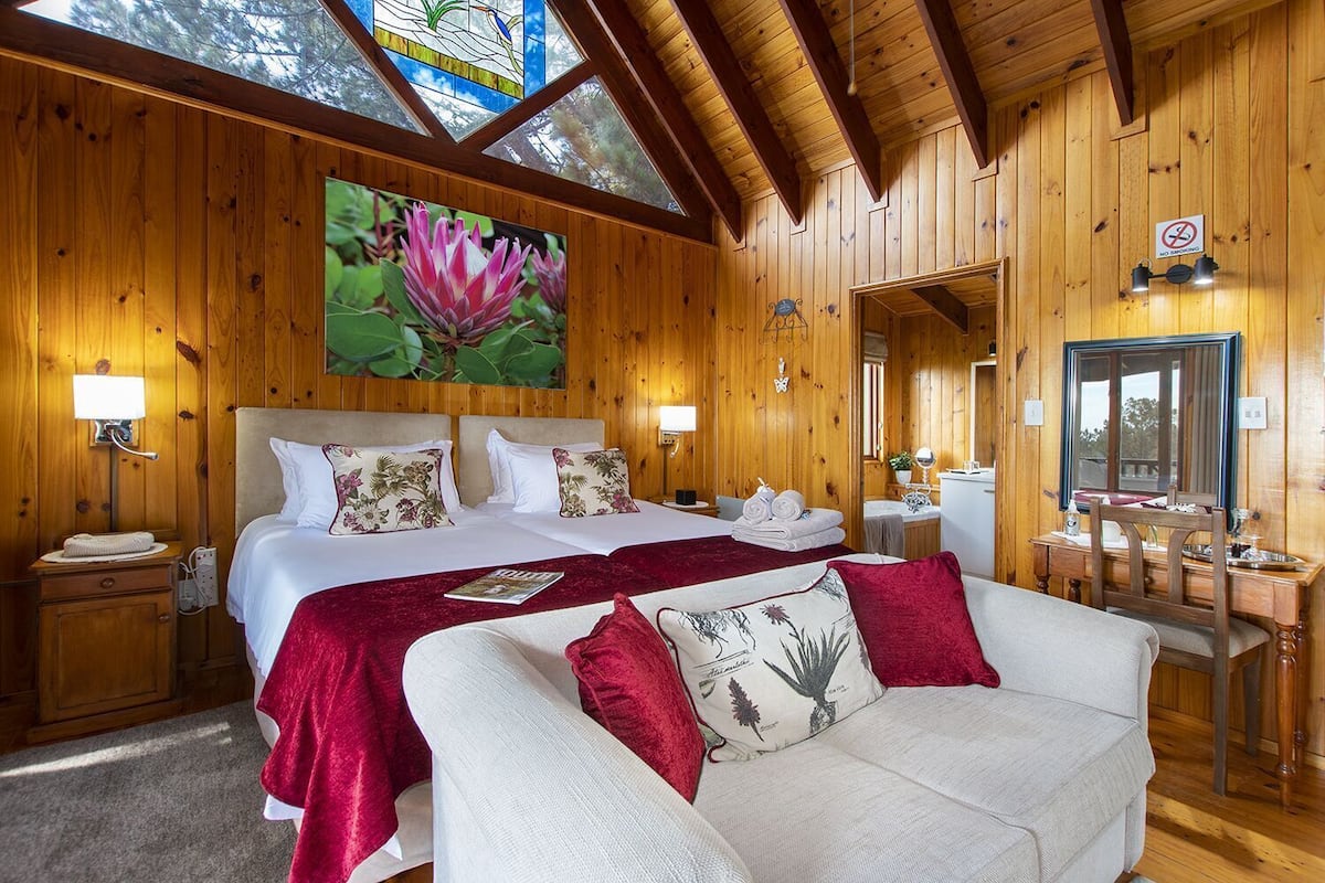 A wooden room with a bed, a sofa, a mirror, and a 'NO SMOKING' sign.