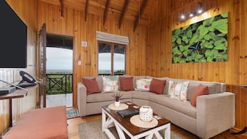 Ein gemütliches Holzinterieur mit einer Couch, einem kleinen Tisch und Blick ins Freie.