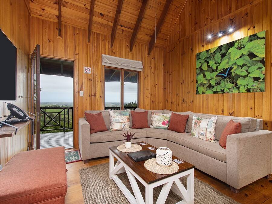 Ein gemütliches Holzinterieur mit einer Couch, einem kleinen Tisch und Blick ins Freie.