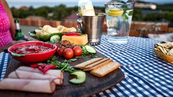 Enjoy a gourmet picnic experience in our serene outdoor dining area, complete with a selection of cheeses, meats, and fresh vegetables.