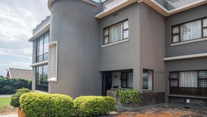 A modern two-story house with a curved corner, large windows, and a stone-paved entrance.