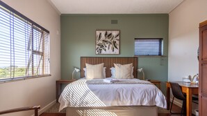 A bedroom with a bed, bedside tables, a desk, and a chair.