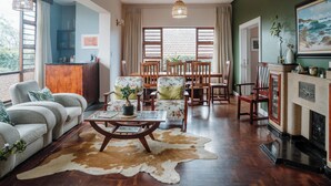 A spacious living room with a large window, wooden furniture, and a cowhide rug.