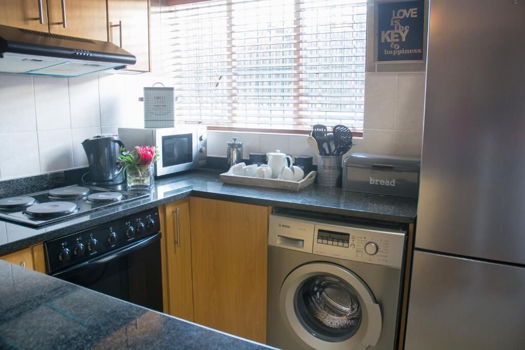 A modern kitchen with a Bosch washing machine, a coffee maker, and a bread maker on the counter.