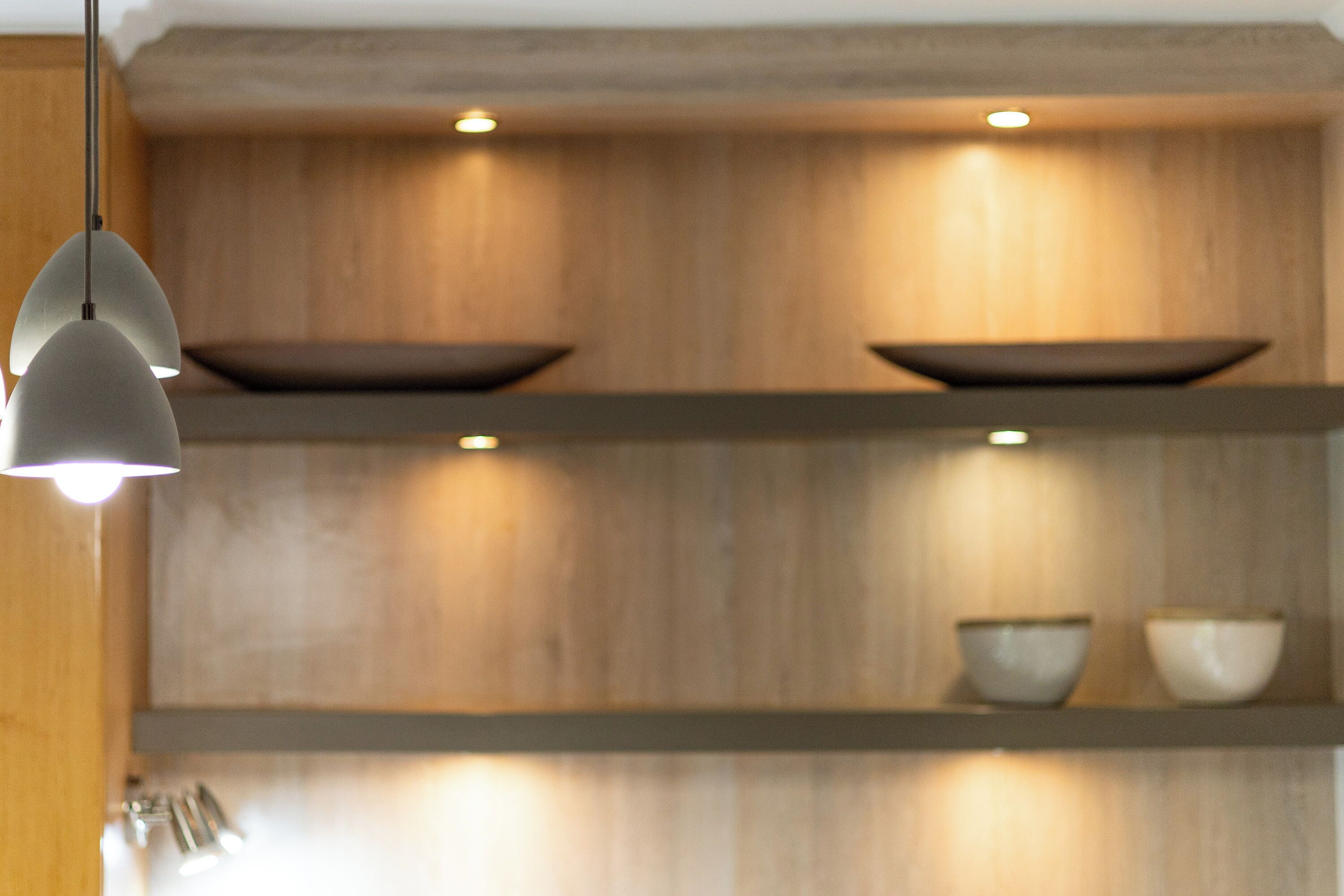 Een keuken met houten kastjes, een hangende hanglamp en twee planken met kommen.
