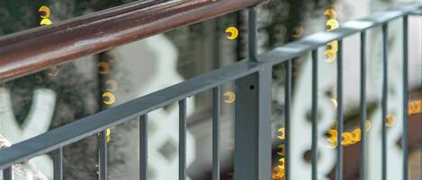 A railing with a blurred background of a building and greenery.