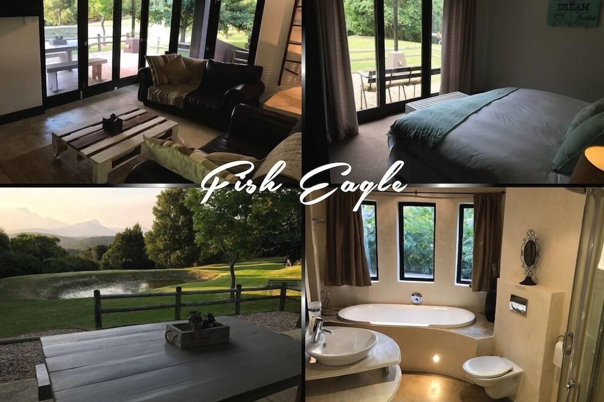 A hotel room with a large window, a sofa, a bed, a dining table, and a bathroom with a bathtub and sink.